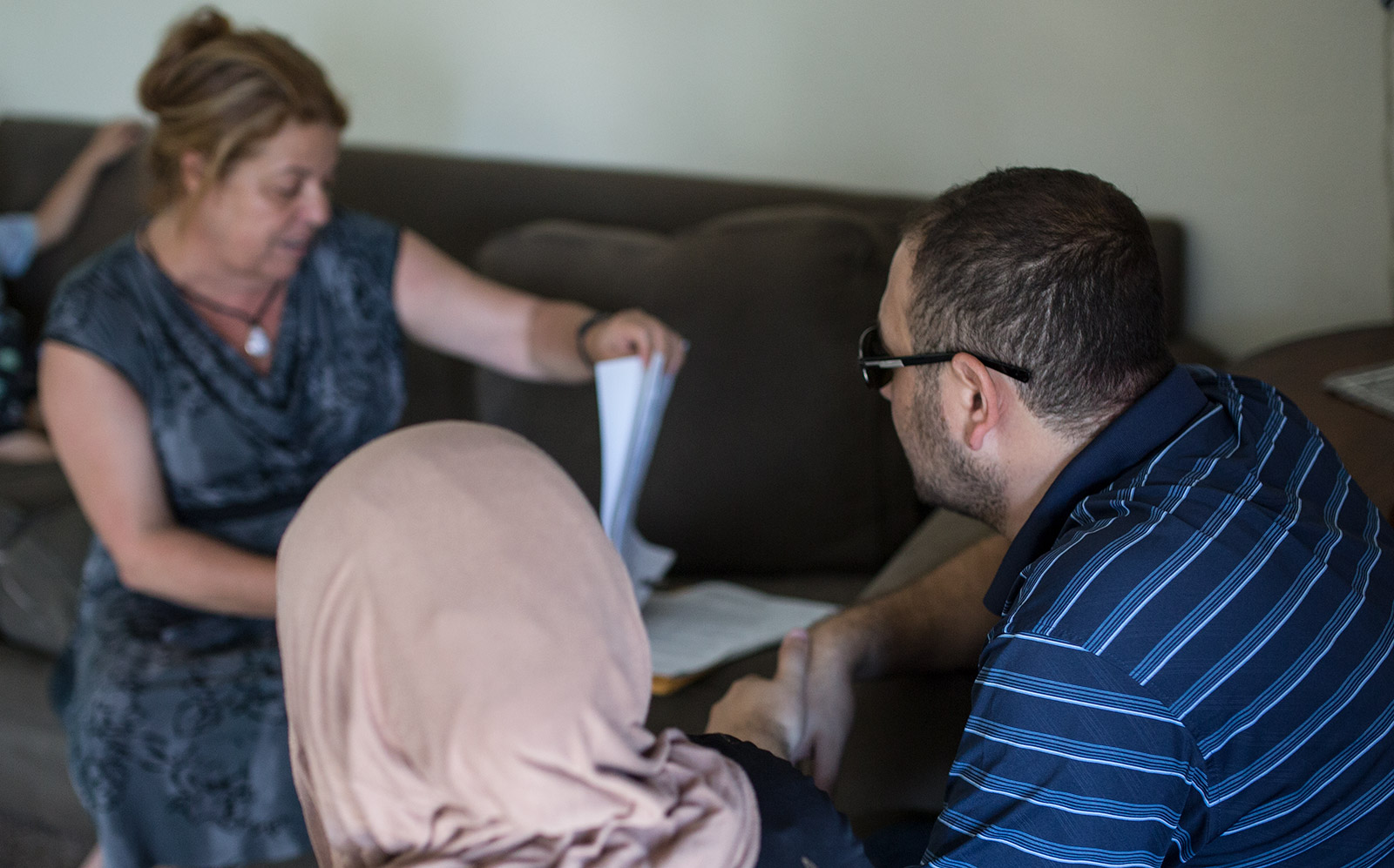 Translator and family friend, Lina Abi-Samra, reviews the lease for the new three-bedroom apartment of Mostafa Inezan (far right), his wife (left) and their five sons, July 25, 2017. Photo by Megan Wood, inewsource.