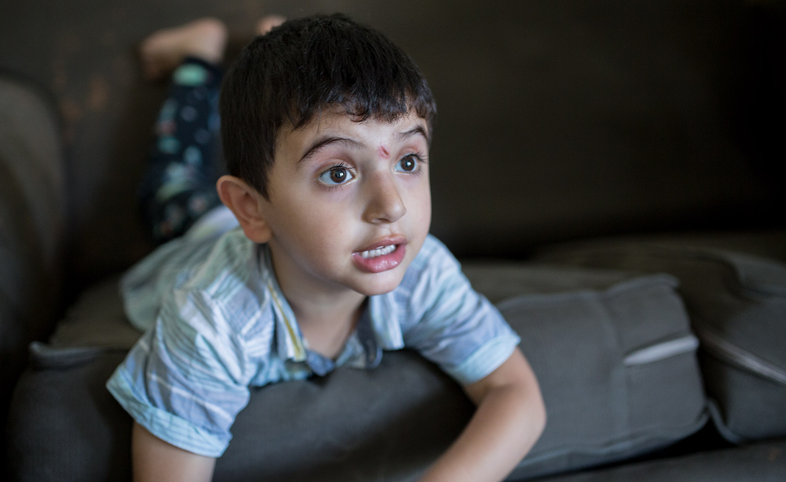 One of Mostafa Inezan's sons plays on the couch in the family's new three-bedroom apartment, July 25, 2017. Photo by Megan Wood, inewsource.