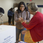A poll worker hands out stickers at the San Ysidro Library on Election Day.